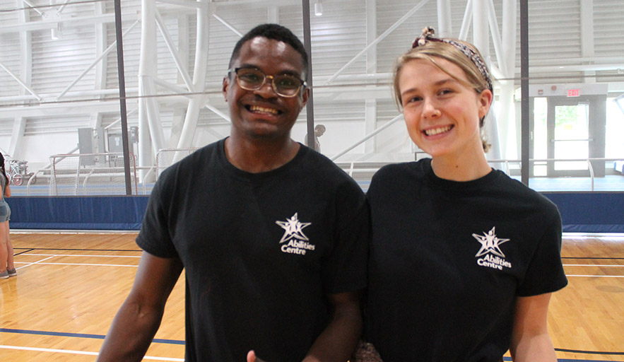 Two Abilities Centre staff coordinators actively smiling in fieldhouse